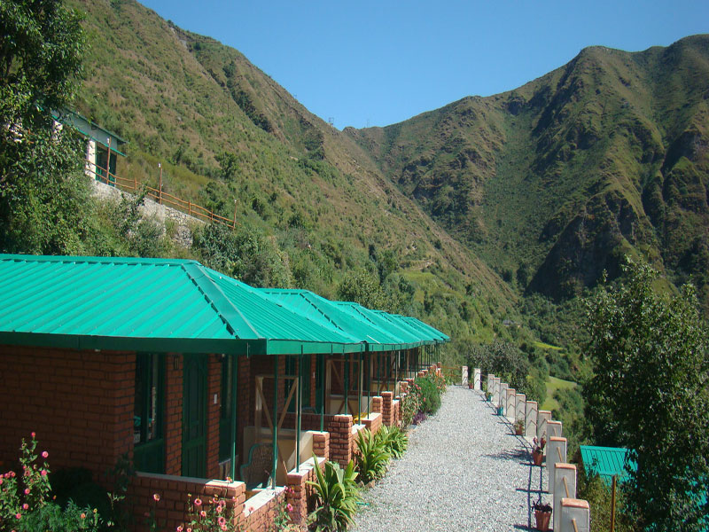 Mountain slope view of brick cottages with green roofs at Chakrata Camps & Cottages