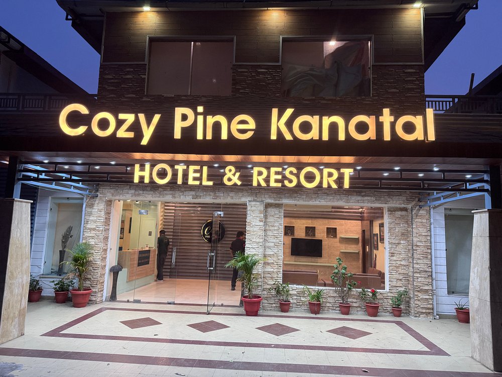 Lit entrance facade of Cozy Pine Kanatal Hotel and Resort with glowing neon signage