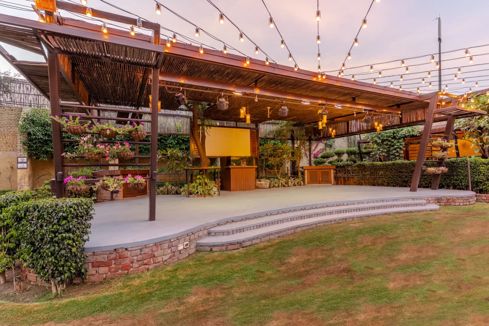 Outdoor stage pergola with fairy lights and manicured event lawn at Aravali Resort
