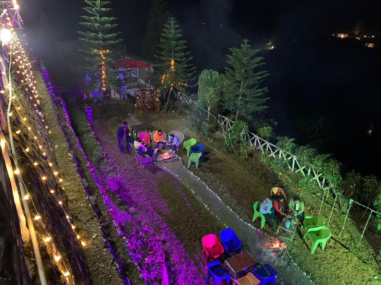 Evening lawn gathering with campfire and festive fairy lighting at Byasi Camps