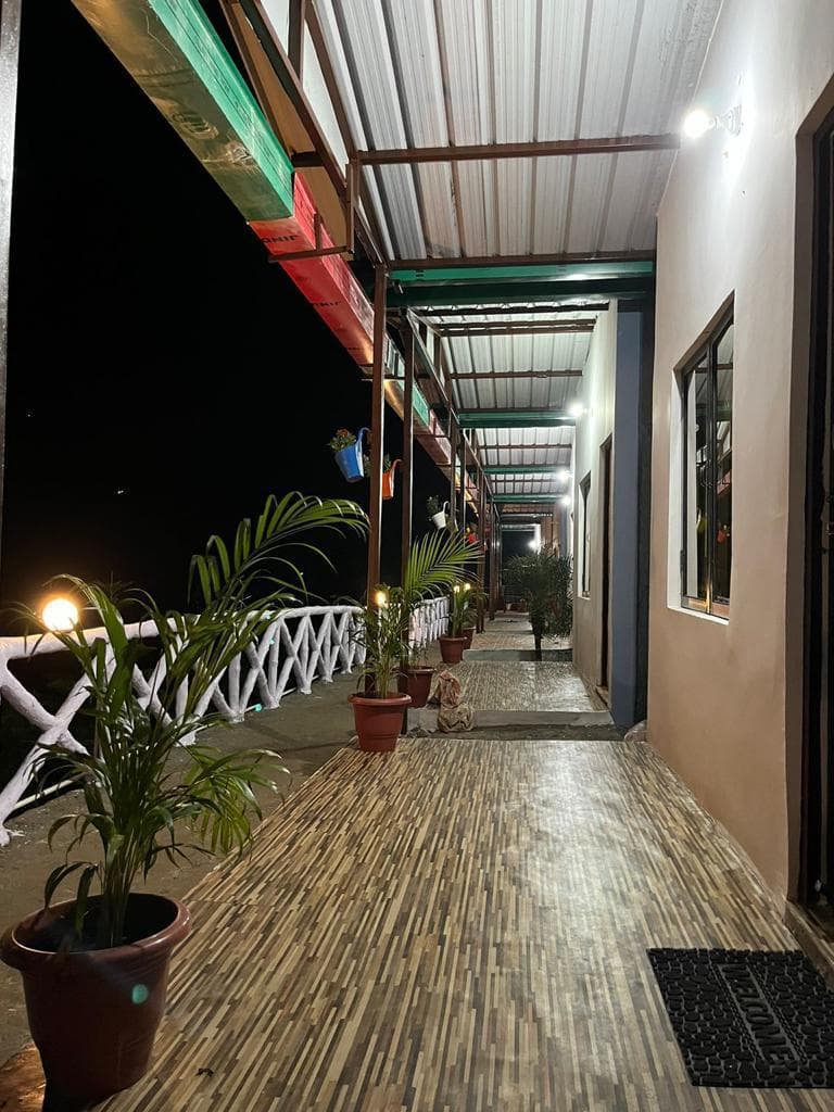 Nighttime view of illuminated covered cottage veranda at Byasi Camps