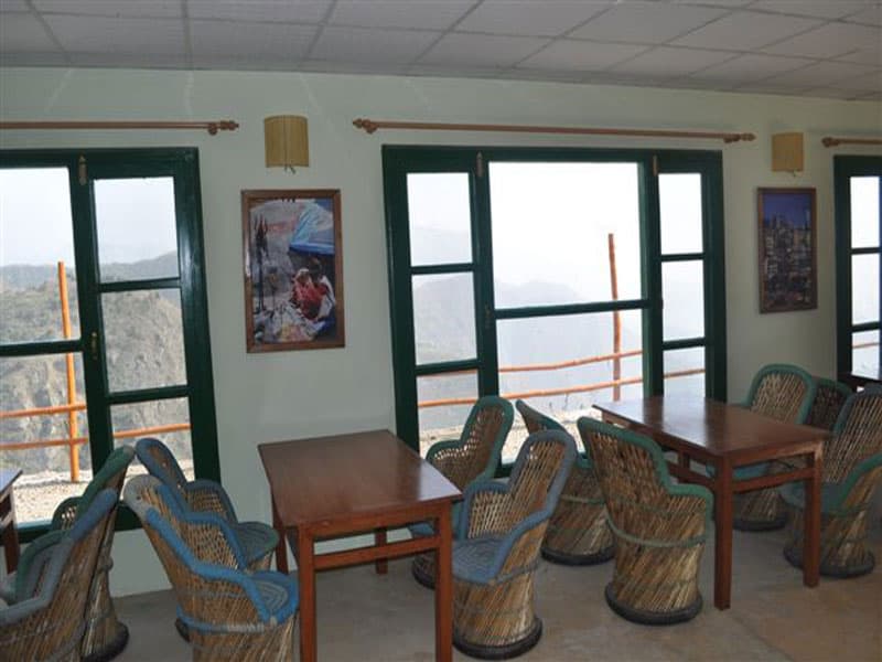 Dining hall with valley view windows and wooden tables at Chakrata Camps & Cottages