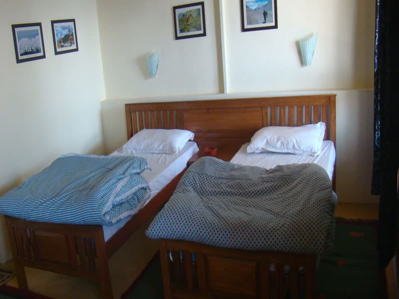 Cottage bedroom interior with wooden beds and warm quilts at Chakrata Camps & Cottages